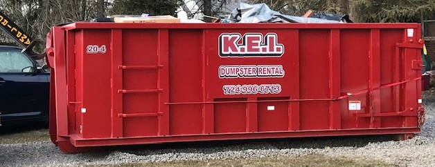 A full KEI dumpster rental services dumpster sits on location at a home. 