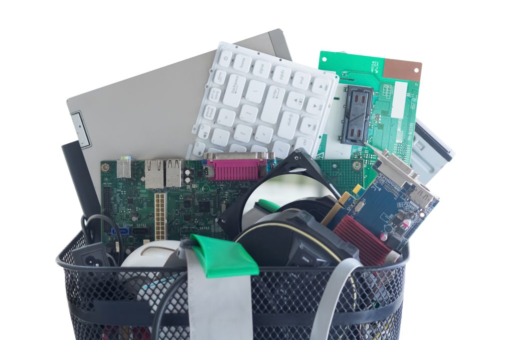 A basket filled with electronic waste items like computer parts, keyboards, and other e-waste that can't be thrown in the regular trash. 