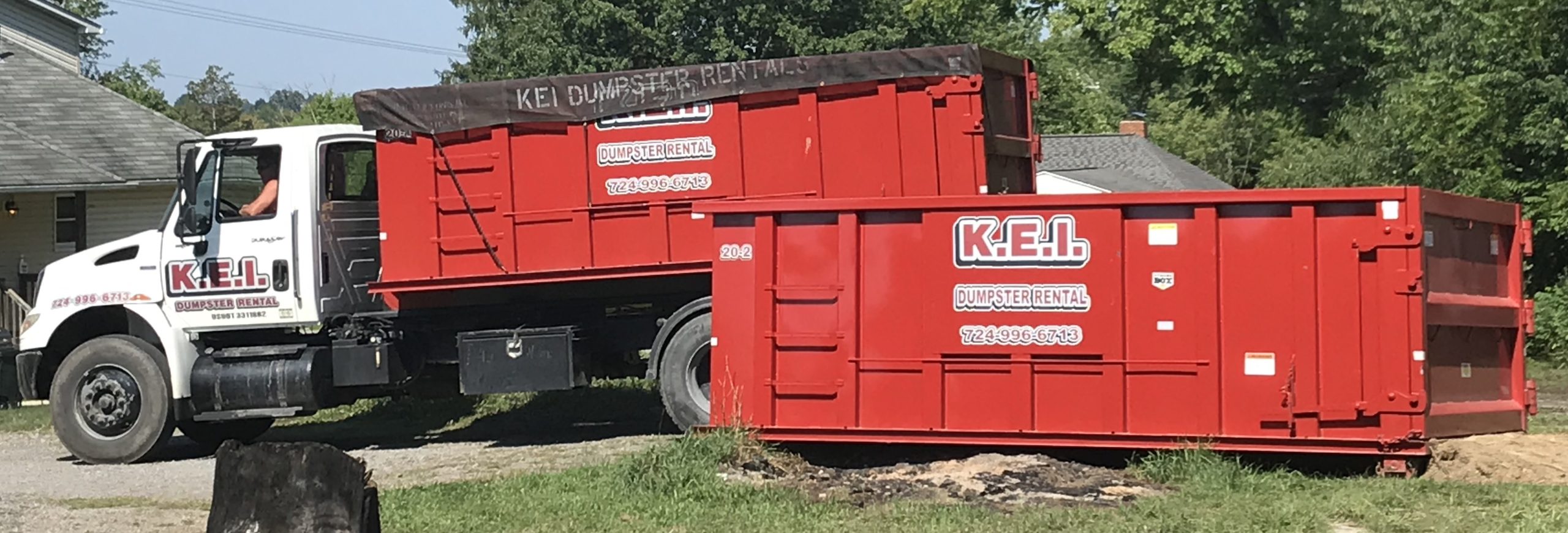 A KEI delivery truck unloads 2 roll-off dumpster rentals in dumpster sizes requested by the customer.