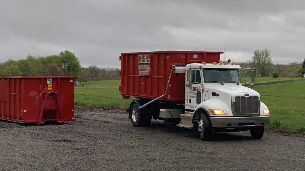 A KEI dumpster delivery truck picks up a full dumpster and leaves an empty one for a client requesting local dumpsters. 
