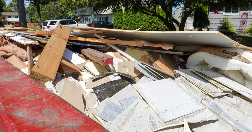 A dumpster overloaded with construction debris sits on a construction site. 