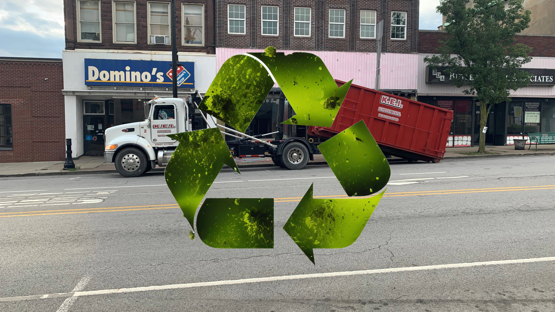 A KEI dumpster rental truck delivers a commercial dumpster rental to a business in Butler. The green "sustainability" symbol appears over the image.