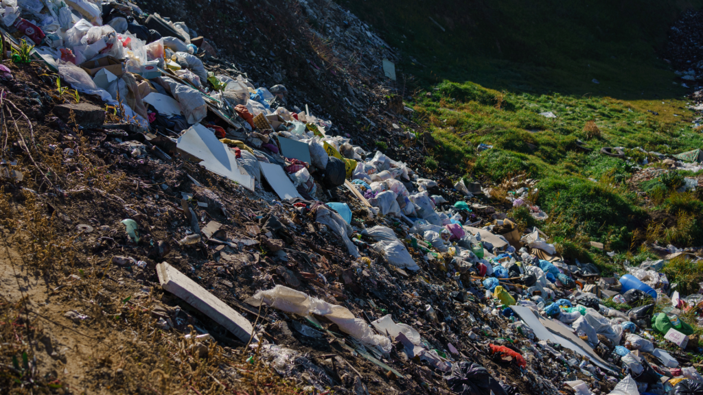 A hillside is pictured with a bunch of trash illegally dumped there. 